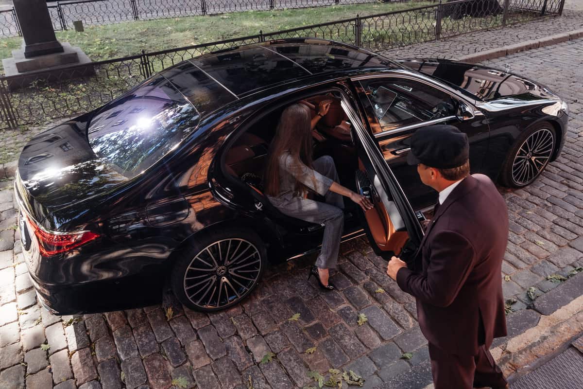 chauffeur helping woman out of limousine